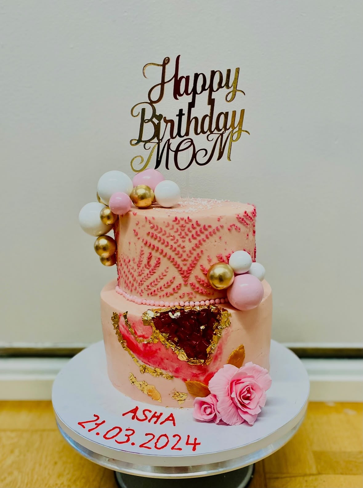Rosa Geburtstagstorte mit Rosen, goldenen Details und Happy Birthday Mom Topper.